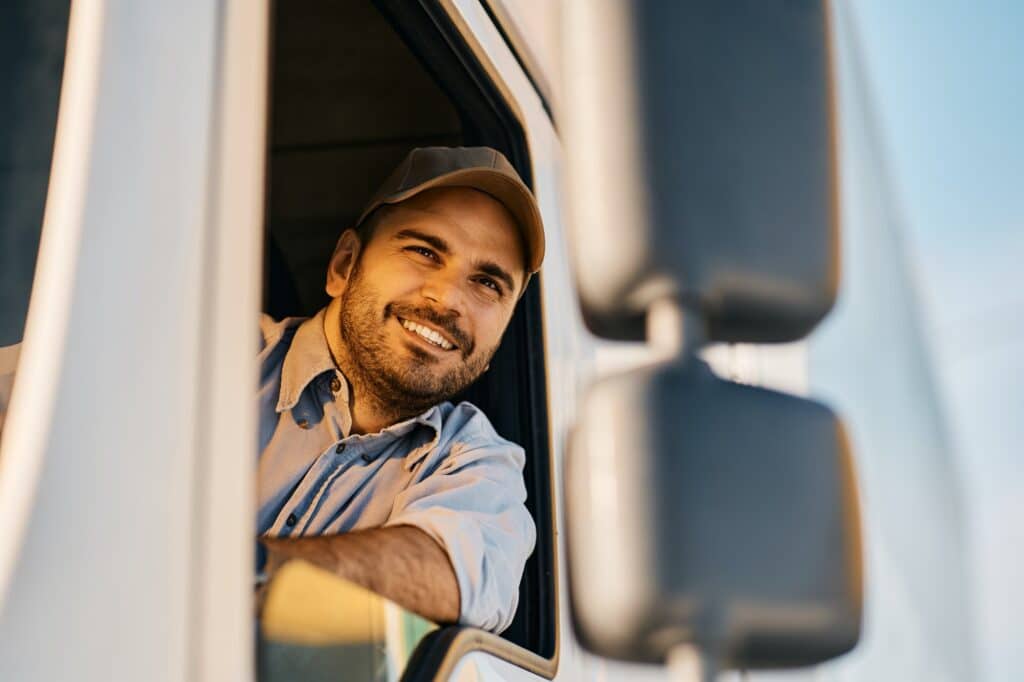Happy truck driver looking through window from the vehicle cabin.